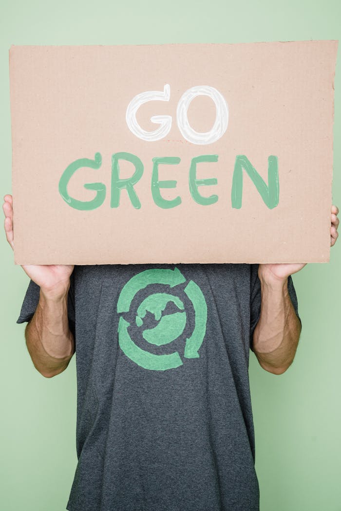Person holding a 'Go Green' sign promoting environmental sustainability.